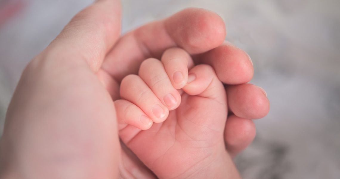 Une personne tient dans sa main la main d'un enfant après un test ADN