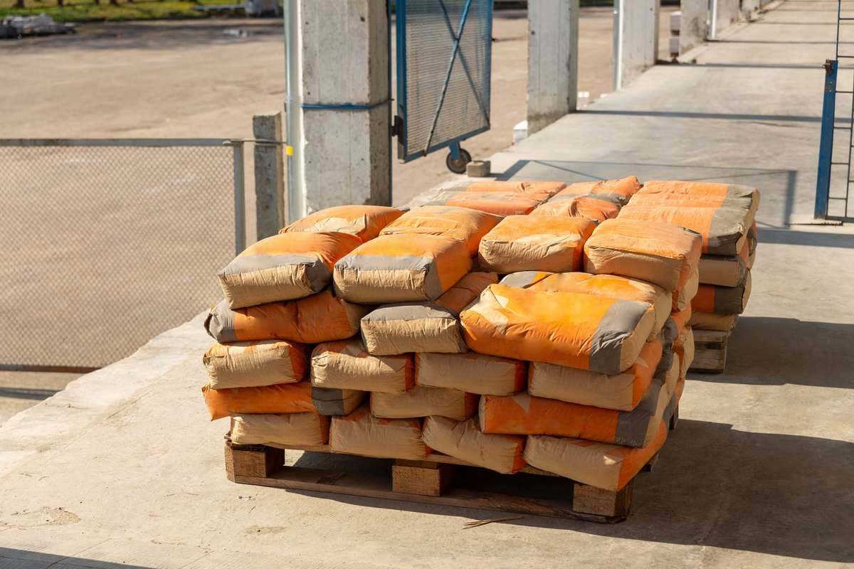 Des palettes de sacs orange empilés sur un sol bétonné à l'extérieur