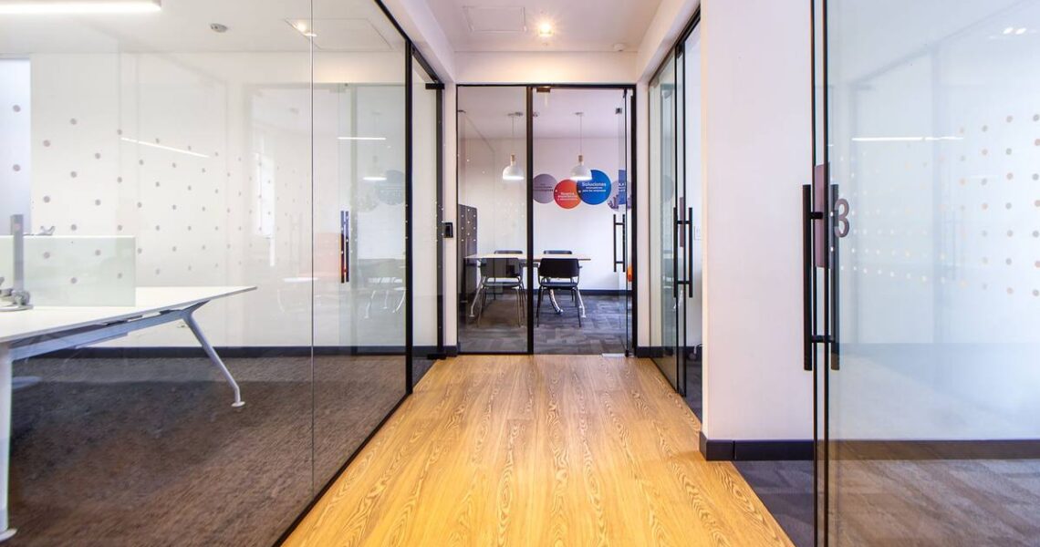 Couloir moderne avec parquet, cloisons vitrées et salle de réunion