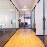 Couloir moderne avec parquet, cloisons vitrées et salle de réunion